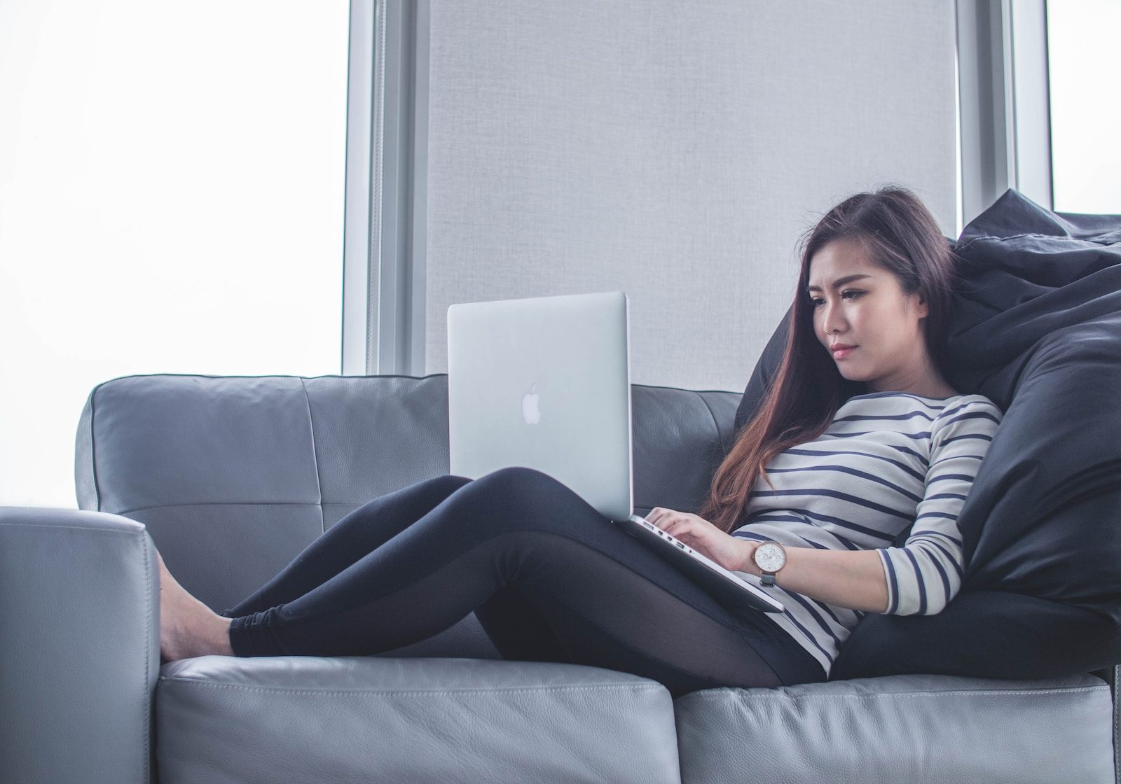 woman sitting on sofa while using MacBook Pro